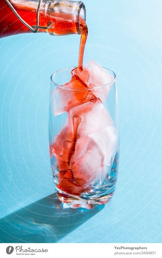 Strawberry syrup pouring over ice cubes in a glass beverage blue bright close-up cocktail cold cold drink colorful copy space crystal clear delicious detox