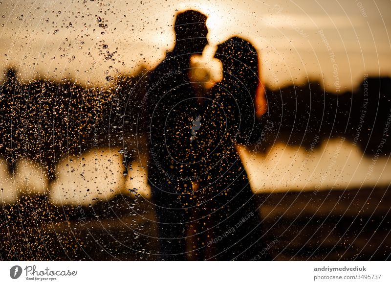 silhouette of loving couple hugging on the lake at sunset. Beautiful young couple in love walking on the shore of the lake at sunset in the rays of bright light. copy space. selective focus