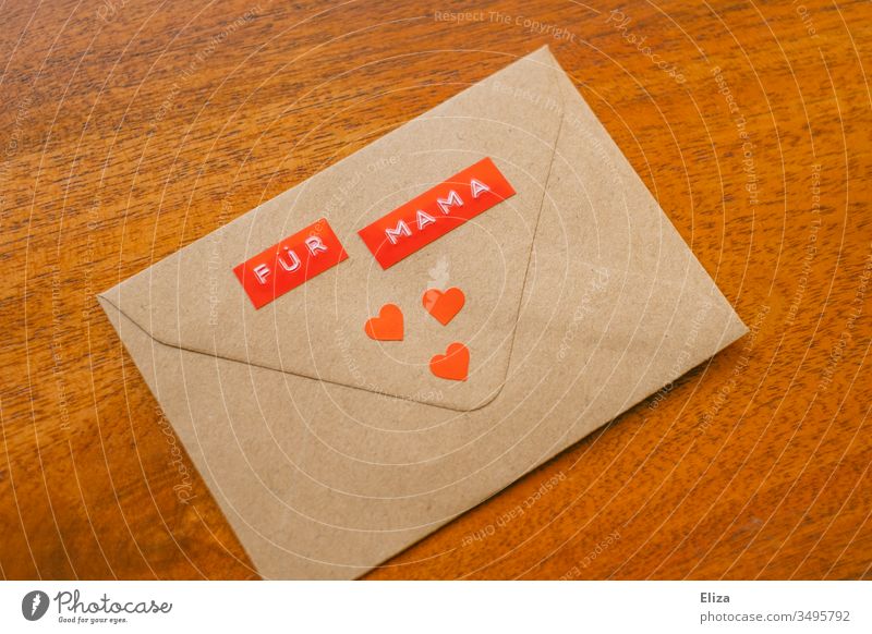 An envelope on the For Mama stands decorated with three red hearts on a wooden background; message gift to the mother on Mother's Day mama Envelope (Mail)