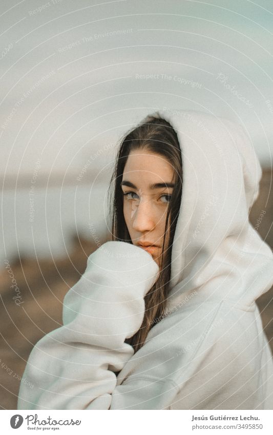 young hooded woman in a white sweatshirt with a serious look vintage background hair Face girl people Exterior shot Beauty Photography attractive Lifestyle