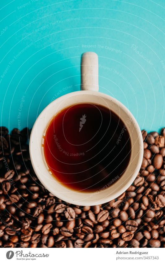 Closeup overhead shot of a cup of coffee with coffee beans on a blue background drink cafe young lifestyle beverage table aroma warm casual mug indoors break
