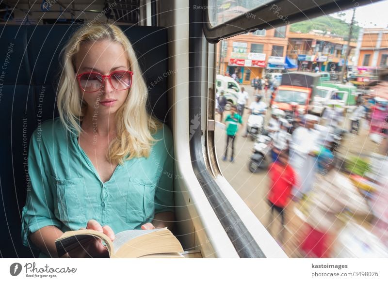 Blonde caucasian woman reading book on train by the window. travel transportation adveture journey indoors relaxing side view vacation on the move sitting