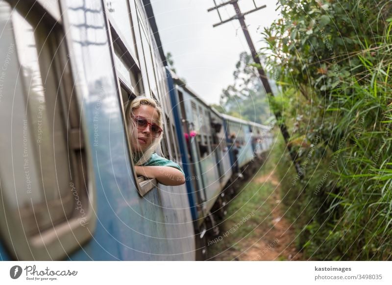 Blonde caucasian woman riding a train, looking trough window. travel transport railway transportation adventure passenger journey indoors relaxing vacation