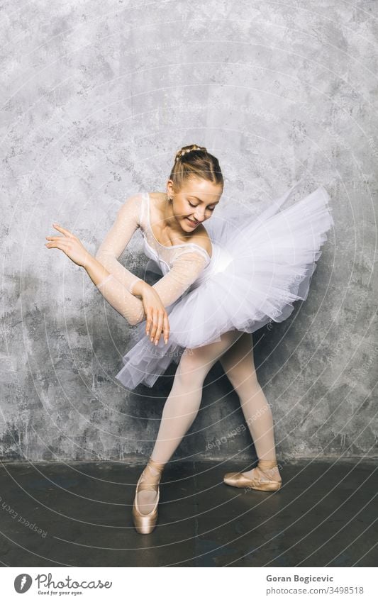 Pretty young ballerina dancer dancing classical ballet against rustic wall woman pose exercise beautiful female shoes dress balance action performer elegance