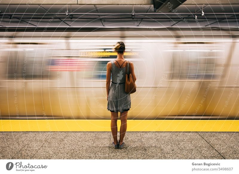 Young woman waiting for subway train in New York City city people metro move transit railroad station underground travel transportation urban girl tunnel motion