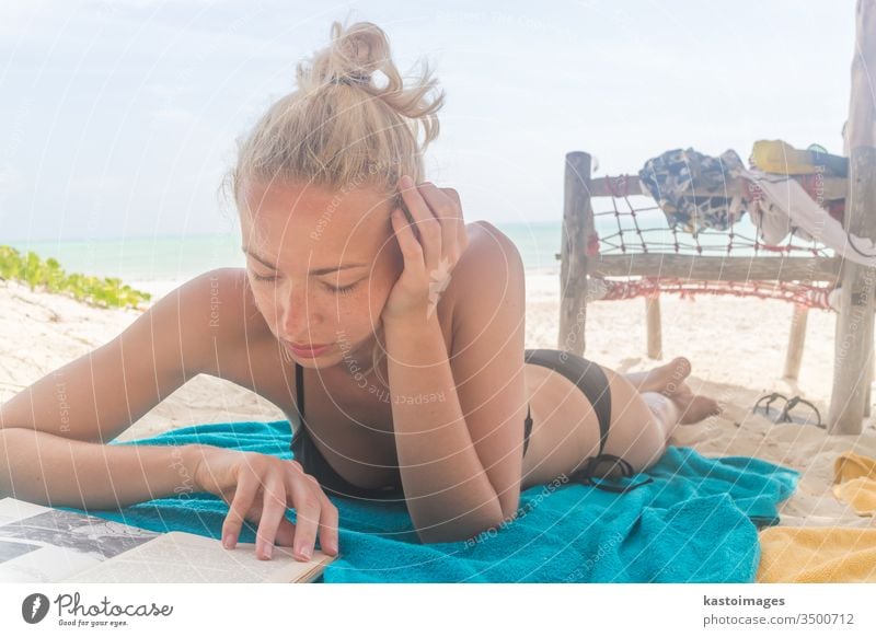 beautiful young woman in black bikini laying in the sunshine on the beach  in the sand - a Royalty Free Stock Photo from Photocase