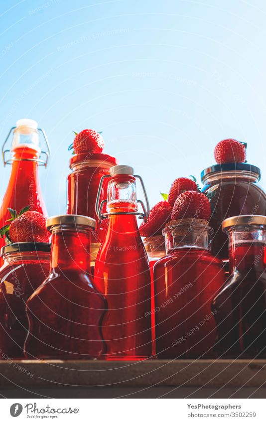 Glass bottles and jars with strawberries syrup and jam containers delicious dessert food fresh fruit syrup fruits full glass bottle glass vessels