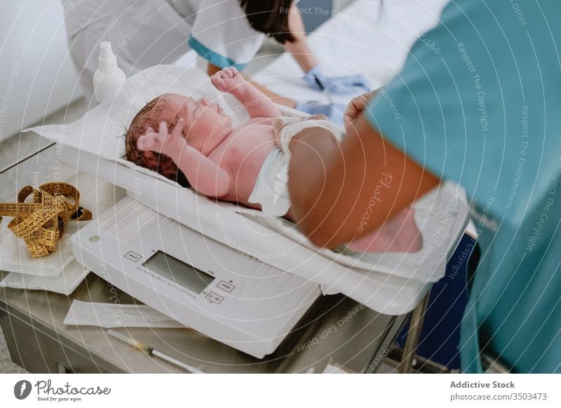 Nurse examining newborn baby in hospital weight scale clinic postnatal examine care healthy child health care doctor nurse childbirth control measure tiny