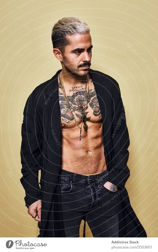 Provocative shirtless man in black coat sunglasses macho cool trendy brutal tattoo style fashion unshaven model personality muscular jeans beard male ethnic
