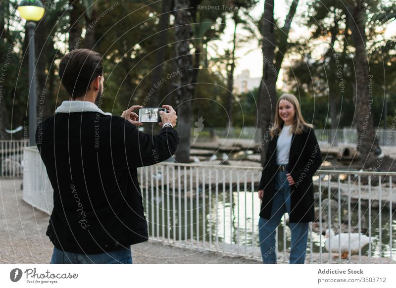 Man taking photo of girlfriend in park couple take photo smartphone city street gadget device screen together relationship lifestyle love using romantic casual