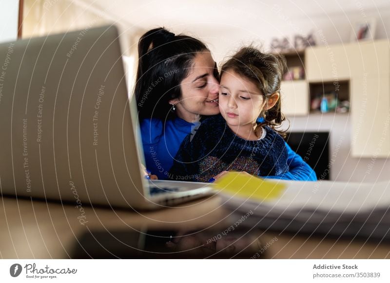 Mother playing with daughter and working on remote project mother hug laptop using home bother love woman girl little freelance child kid parent together