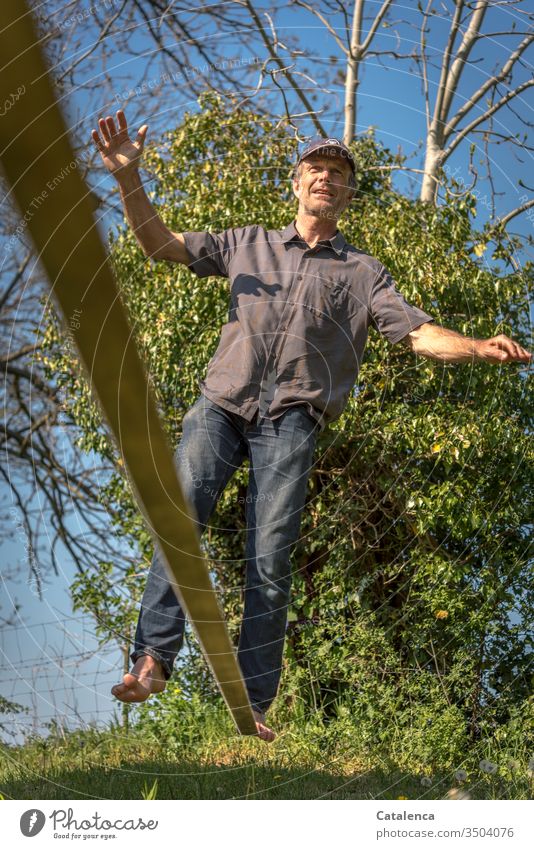 In balance on the slackline Man Human being Adults Masculine Balance balancing walk balancing act Full-length Summer Day Contentment Grass Ivy Tree Sky