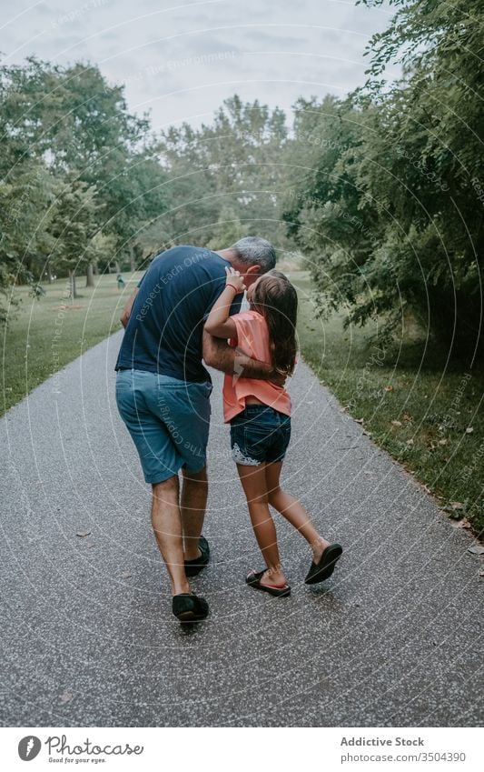 Father with daughter walking in park father secret whisper together talk relationship kid communicate love parent conversation hug casual child dad lifestyle