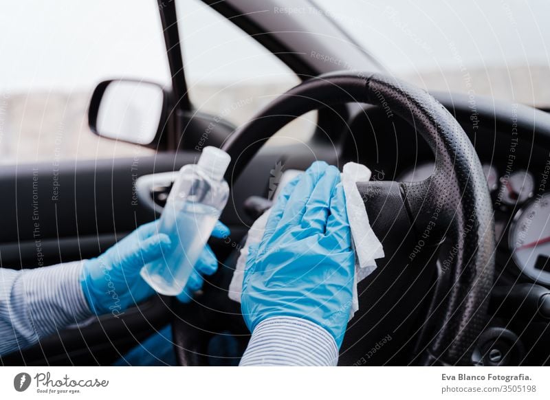 unrecognizable man in a car using alcohol gel to disinfect steering wheel during pandemic coronavirus covid-19 disinfecting get automobile transport wipe job