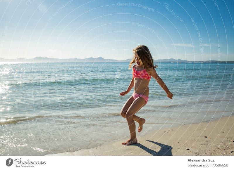 Girl enjoying sea jumping over waves spending a free time over sea on a  beach during summer vacation - a Royalty Free Stock Photo from Photocase