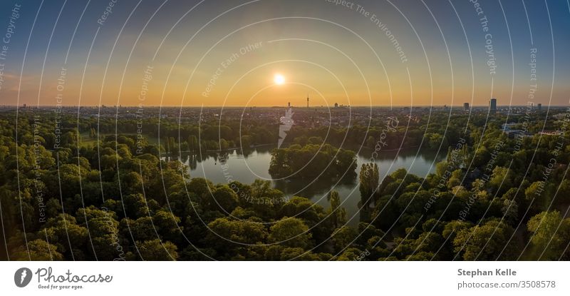 An idyllic park in the Englischer Garten of Munich with a beautiful lake as an aerial. munich nature beatyful sunset drone sky trees green summer boat skyline