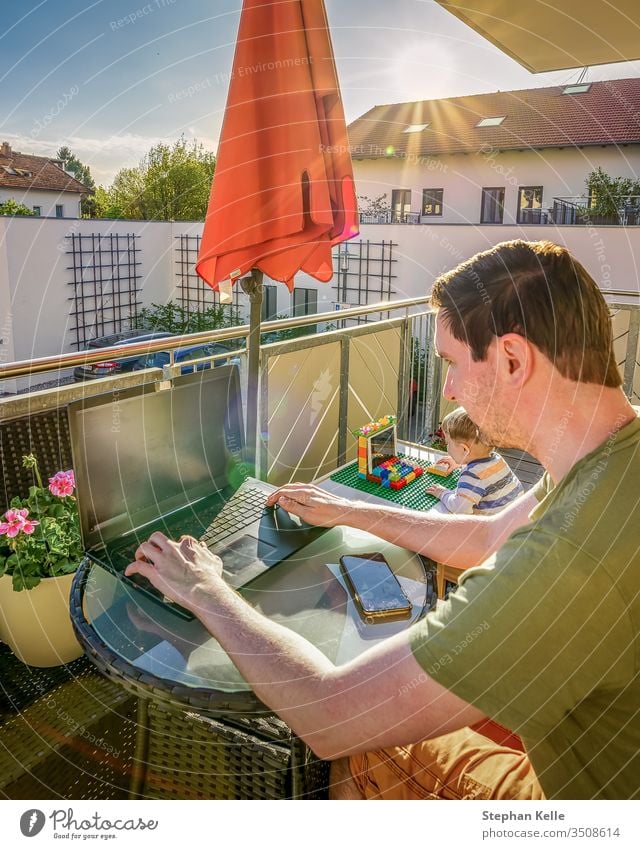 The Ministry of the Interior, father and son work together with their laptops at home on the balcony while the sun is shining. New lifestyle due to corona, Covid 19 pandemic.