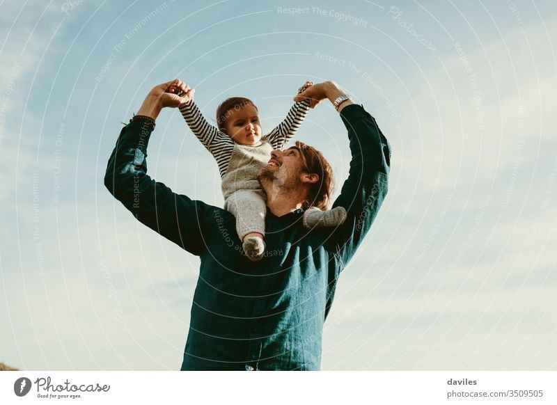 Handsome man giving a piggyback ride to his baby son outdoors. young fatherhood arms handsome male person sky background cute white looking lovely 30s 1 year