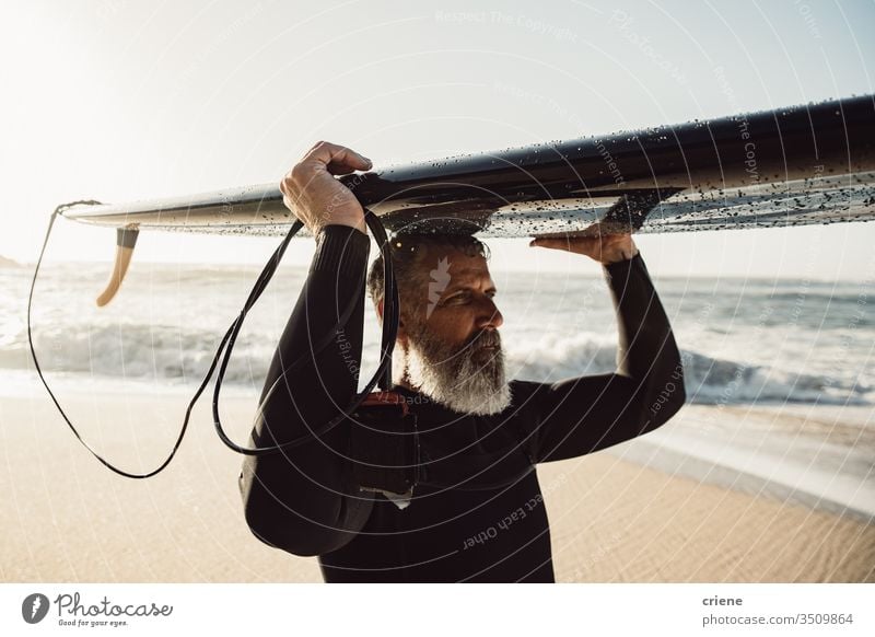Caucasian Senior man with beard carrying surfboard on his head senior men vacation beach surfing adult grey hair lifestyle sport hobby portrait ocean waves