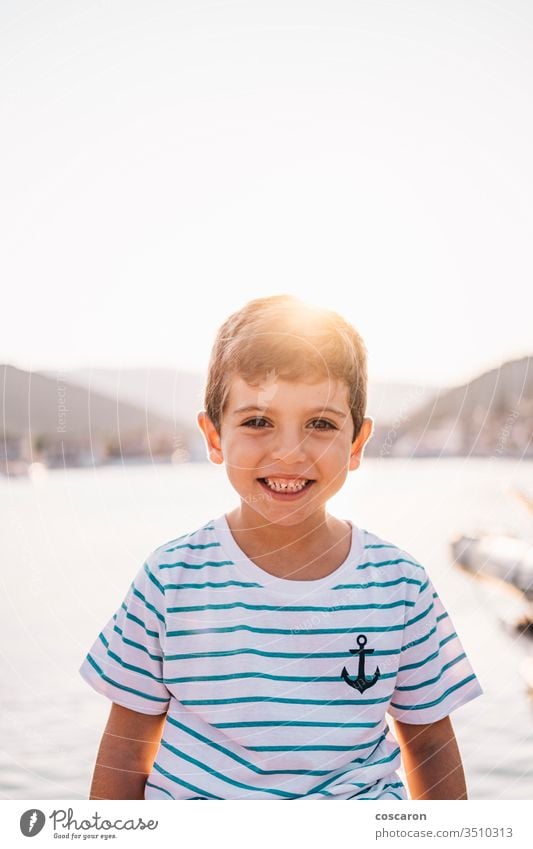 Cute kid smiling at sunset with the sea in the background beach beautiful blue boy bright cheerful child childhood children coast coastline color cute face