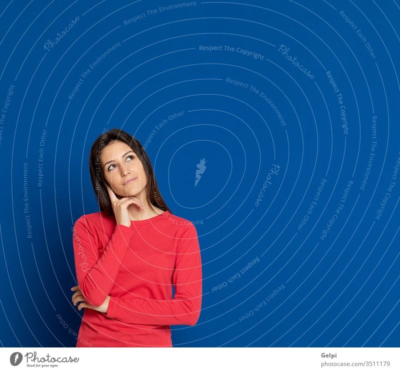 Brunette young woman wearing a red T-shirt girl person blue thoughtful mind finger pensive think imagine imagination idea gesture beautiful female fashion