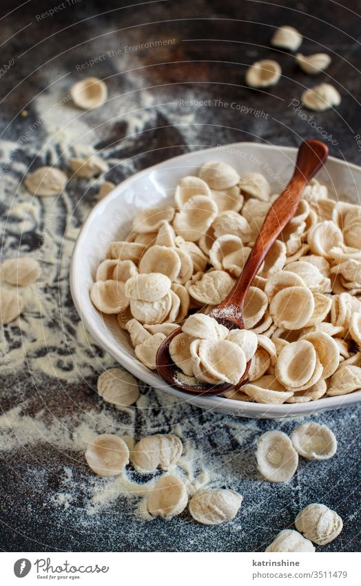 Fresh raw  italian pasta orecchiette apulia fresh dry traditional ingredient close up spoon dark plate diet flour handmade homemade mediterranean organic