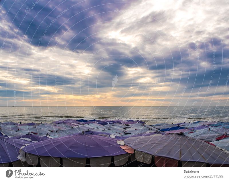 Large umbrella crowded along the beach sky dark cloud cloudy outdoor summer sea blue beauty white holiday travel vacation ocean relax sunlight