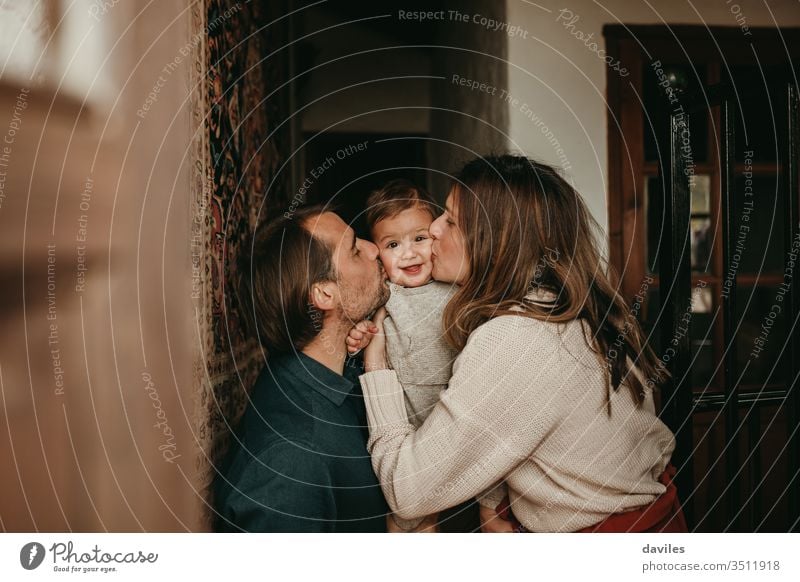 Lovely baby infant being kissed by mom and dad at home. beautiful handsome white indoors smile lovely cheerful positive people room lifestyle light wooden rural