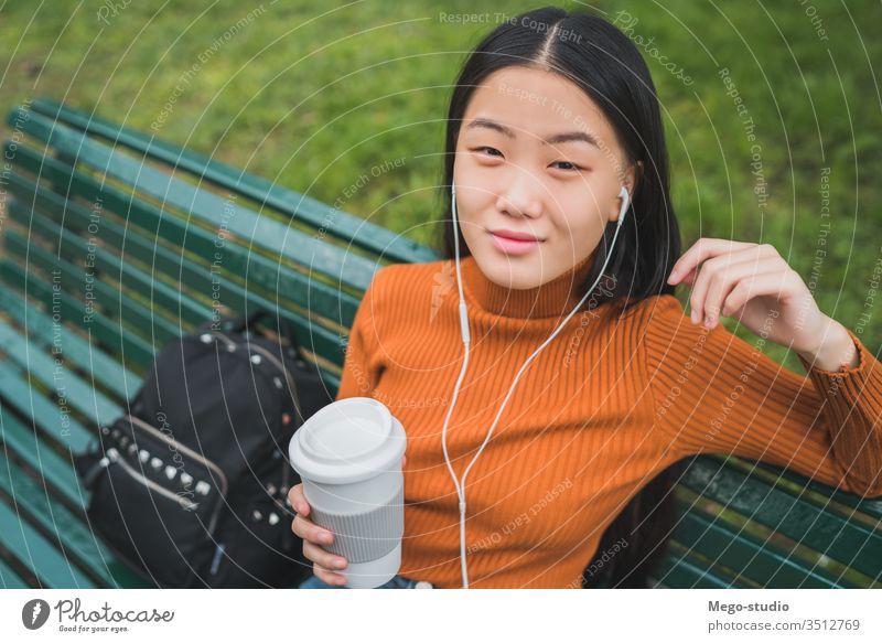 Asian woman listening to music. coffee girl asian park outdoor young beautiful headphones person outside lifestyle chinese female city green people japanese