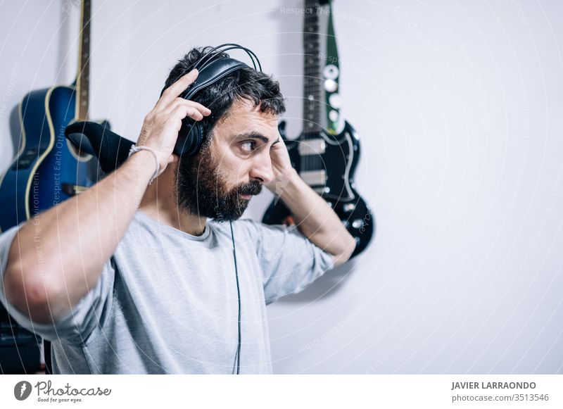 Working sound engineer wearing headphone in home studio. man composer learning guitars headphones artist audio back backgrounds digital entertainment computer