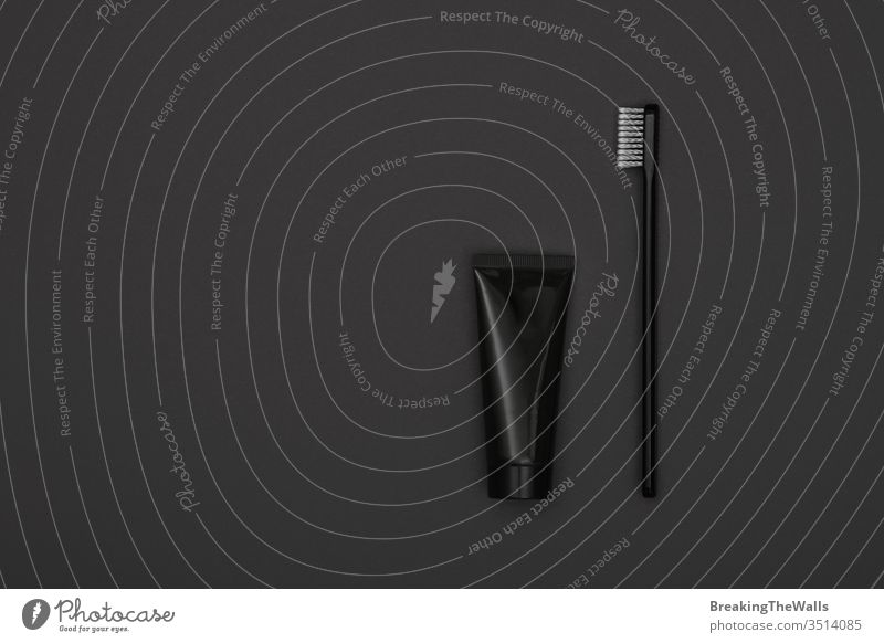 Black toothpaste and toothbrush over grey Toothbrush black tube one closeup copy space dark background dental care hygiene product treatment flat lay layout