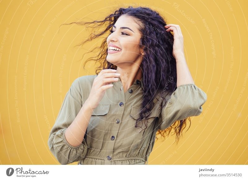 Arab woman with curly hair moved by the wind arab hairstyle smile beautiful girl beauty young one fashion female arabic copyspace middle eastern yellow green