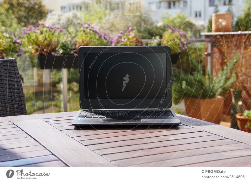 Laptop on terrace table in front of flowers laptop Notebook Computer outdoor Balcony Terrace Window box home office spring labour