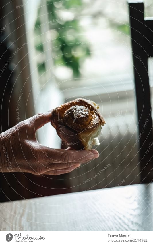 Hand of a woman holding a cinnamon roll hand cinnamon rolls cinnamon cake cinnamon bun Cinnamon eating piece of cake bread Food photograph people natural light