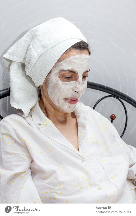 Mature woman taking care of her face with a face mask in bed with dog beauty treatment facial mature laptop covid-19 coronavirus quarantine epidemic job work