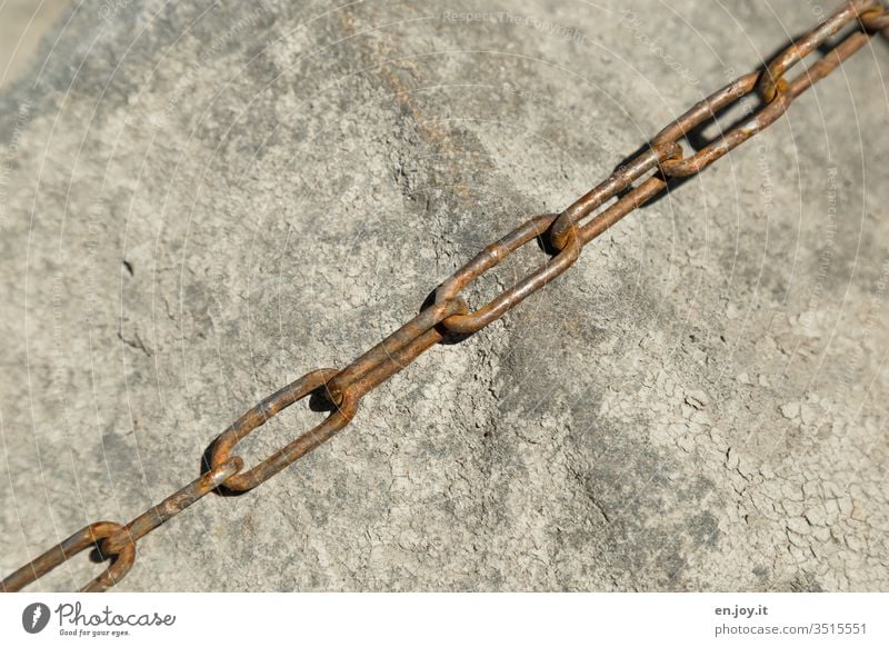rusty iron chain lies on a rock Chain roasted Rust Iron chain limbs Diagonal Rock Stone Backup stop To hold on Protection Metal Deserted Colour photo