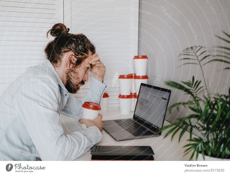 Exhausted young man with beard sitting on the chair and using laptop. video chat online shopping using technology work from home millennial business phone