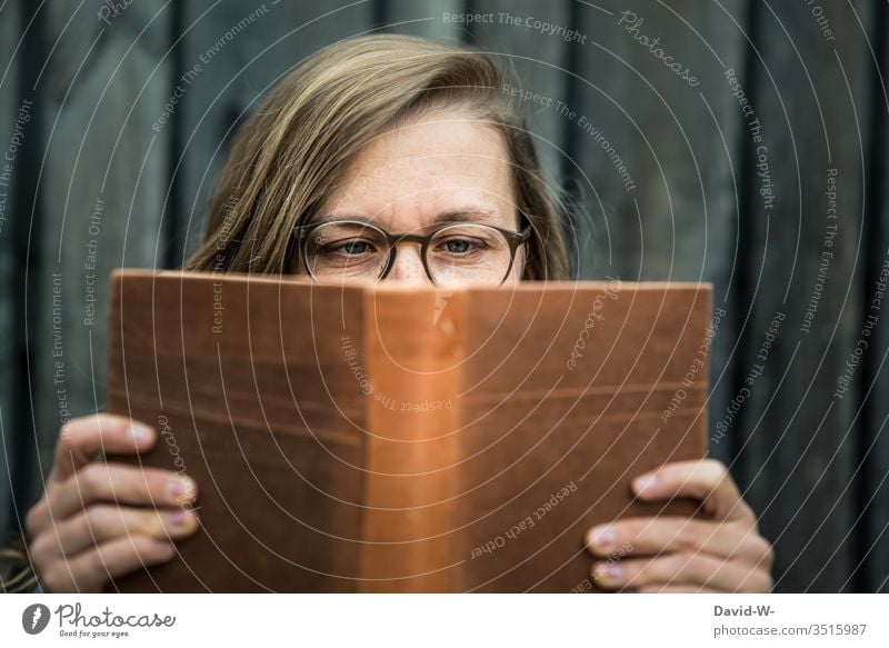 Woman with glasses holds a book in her hands and reads Book Reading youthful Reader hollowed Eyeglasses Nerdy naturally Tension Literature Education