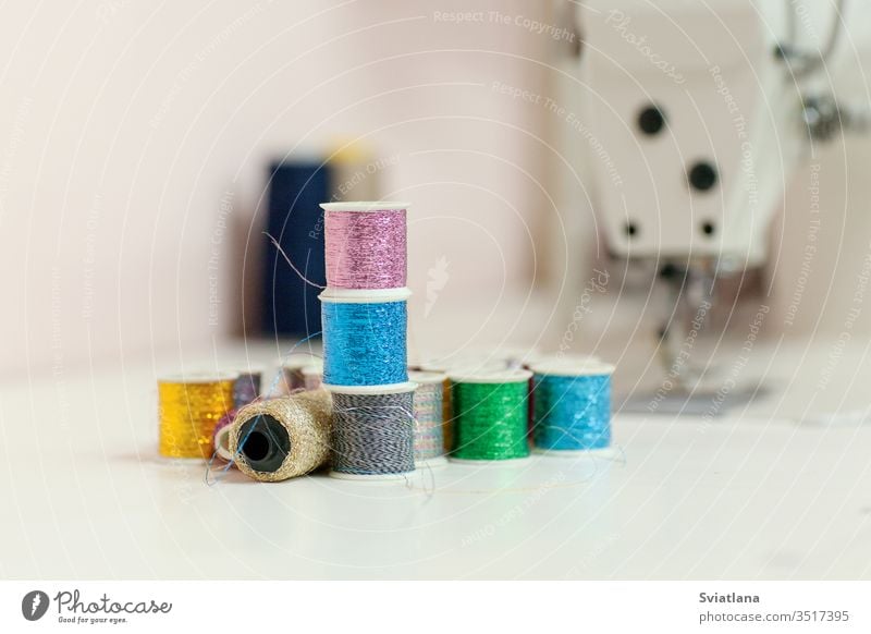 Sewing accessories on the desktop close-up. Sewing threads from lurex in  spools, in the background a sewing machine - a Royalty Free Stock Photo  from Photocase