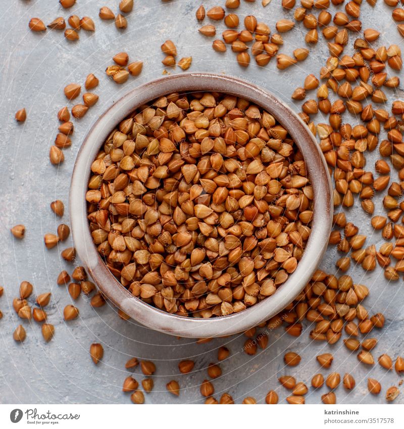 Raw dry buckwheat grain  in a bowl Buckwheat food ingredient gluten free close up plate ceramic top view grey neutral brown rustic cuisine healthy heap pile