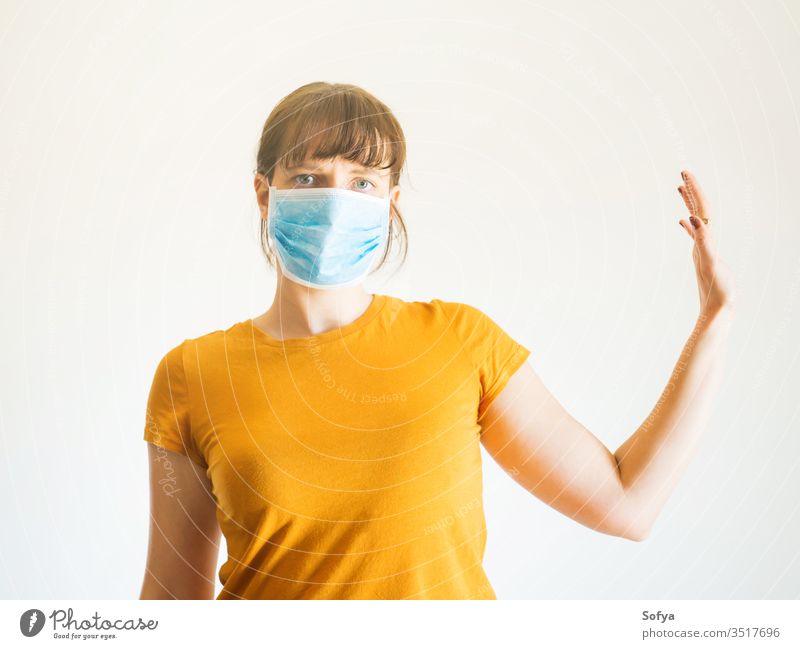 Young woman in face mask with raised arm coronavirus social distancing quarantine hand stop isolated covid19 distant stay home alone protection isolation