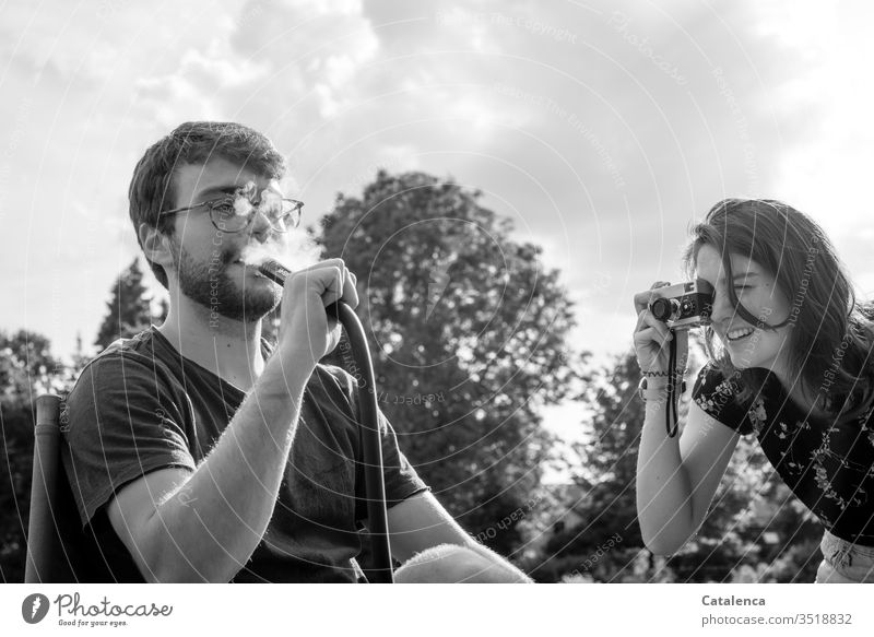 With an analog camera the young woman takes a picture of her brother smoking a hookah Young woman Feminine Human being Young man Masculine taking a photograph