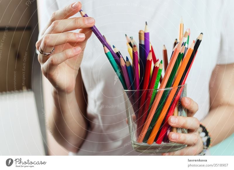 Closeup of woman picking colorful pencils from a glass creativity school drawing artist colored crayon creative designer education equipment female hand hobby