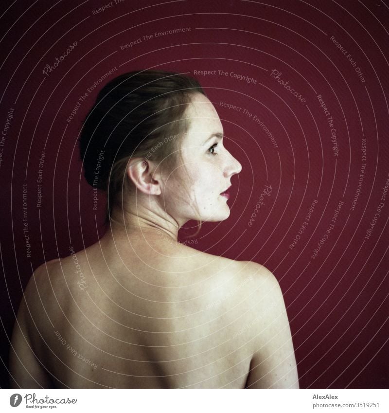 Analogue portrait in rear view of a young woman in front of a red wall Delicate Shadow Light picture-like Athletic Feminine empathy Emotions emotionally