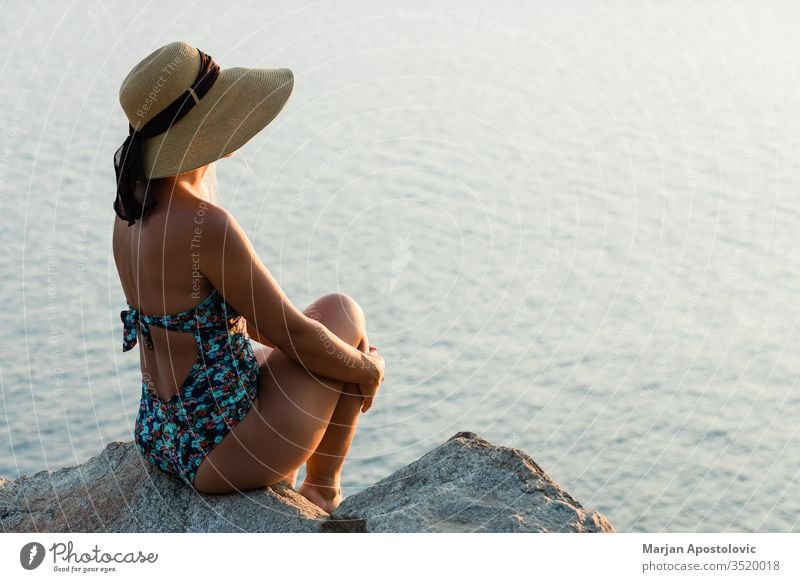 Young woman enjoying sunset by the sea adventure beautiful beauty carefree cliff coast coastal coastline evening female freedom girl hat holiday horizon