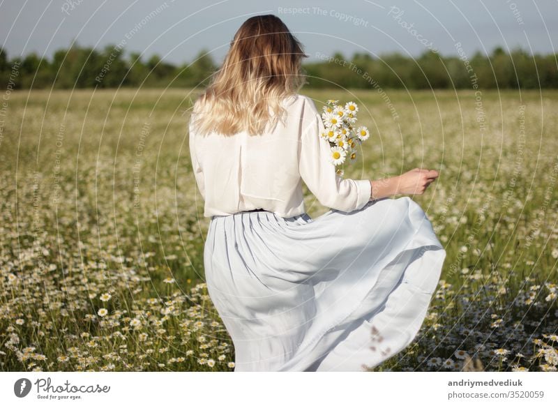 stylish young blonde woman walking in a field with daisies on a sunny summer day. flowers meadow nature people happy portrait beautiful female fun girl smile