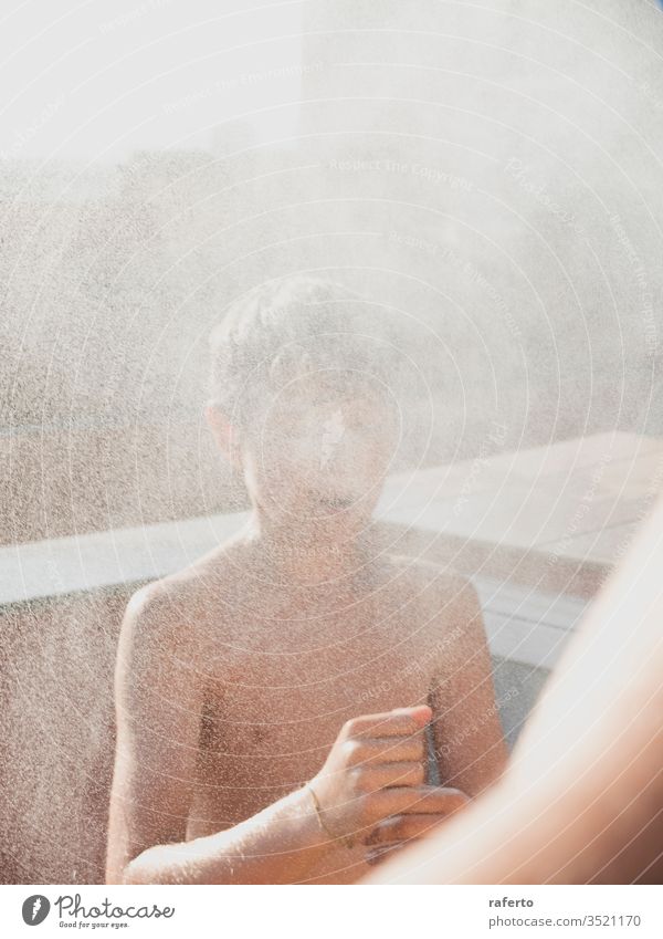 Cheerful young male enjoying a shower by hose outdoors in the terrace boy water garden summer outside children play refreshment pour fun childhood smiling youth