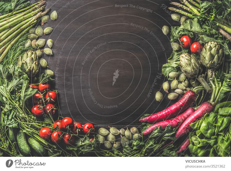 Food background with group of various fresh organic vegetables from garden on dark rustic wooden background. Top view. Healthy clean vegetarian ingredients: Tomato, lettuce, root vegetables,artichokes
