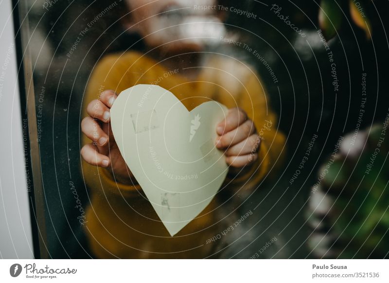 Close-Up Of Hand Holding Heart Shape through window through glass holding Heart-shaped Child at home stay at home Quarantine Window prevention pandemic