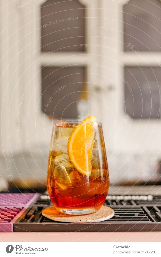 Vertical photo of a crystal glass with an iced cocktail with a piece of orange to decorate in a bar vertical drink alcohol cool freshness dark beverage garnish